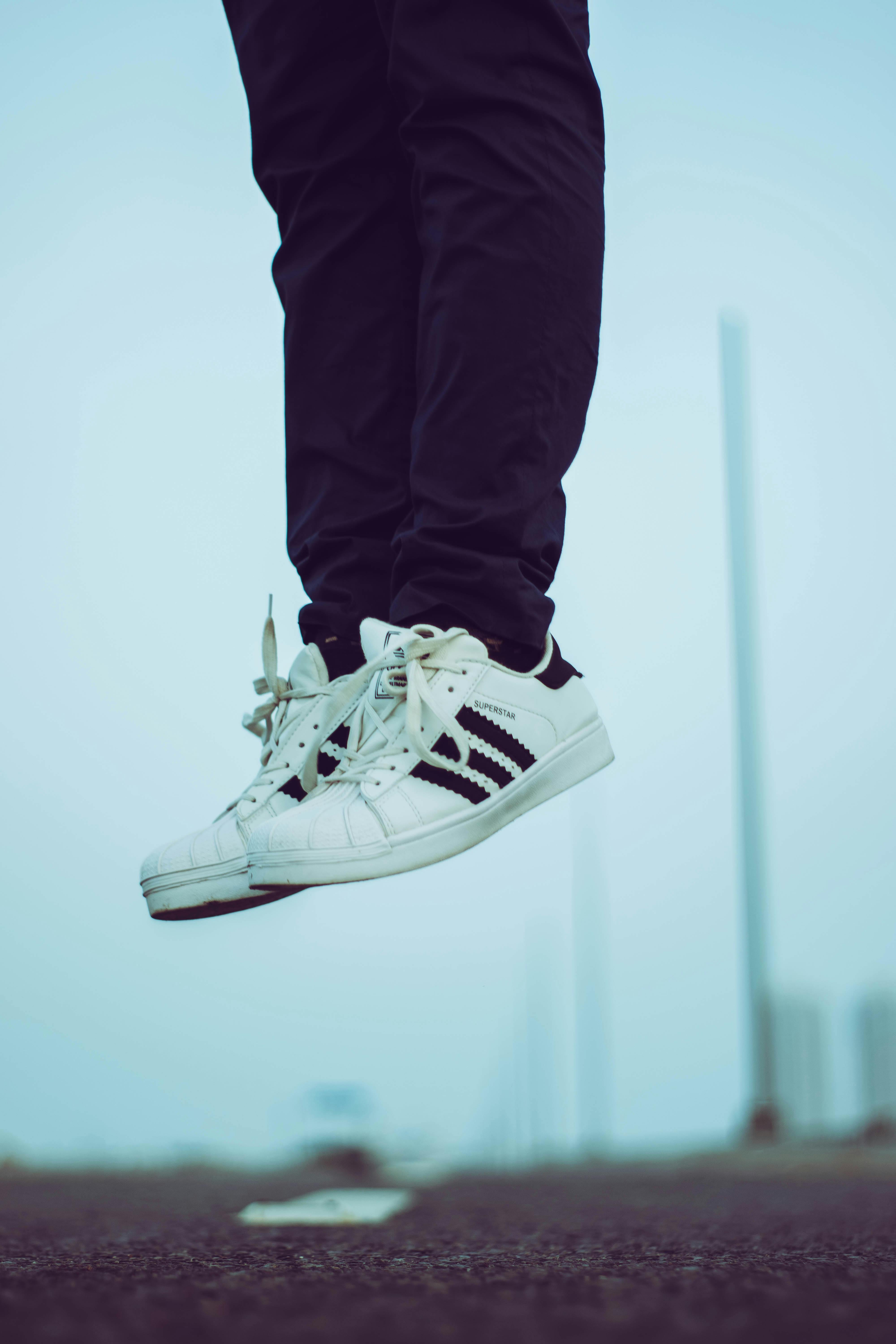 человек в белых туфлях Adidas Superstar · Бесплатные стоковые фото